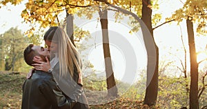 Romantic couple kissing and caressing each other at autumn park with sunset