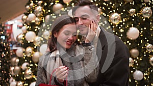 Romantic couple kissing and embracing near decorated Christmas tree