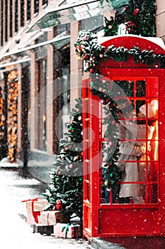 Romantic couple kissing, hugging, having fun in winter before Christmas, standing in red phone booth