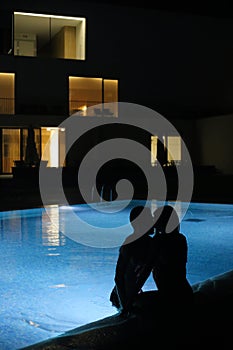 Romantic couple kissing at the pool in the night