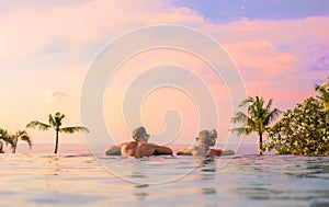 Romantic couple looking at beautiful sunset in luxury infinity pool