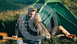 Romantic couple in love camping outdoors and sitting near tent. Happy Man and woman on a romantic camping vacation.