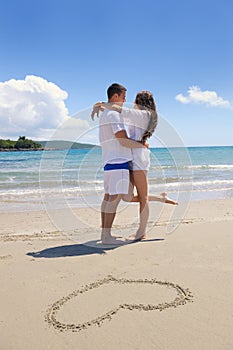 Romantic couple in love have fun on the beach with heart drawi