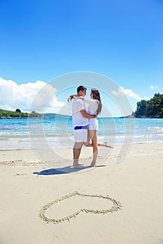 Romantic couple in love have fun on the beach with heart drawi