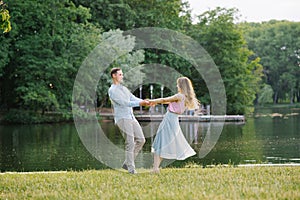 A romantic couple in love holding hands and spinning on the shore of the lake