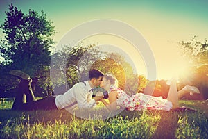 Romantic couple in love kissing while lying on grass. Vintage