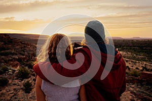 Romantic couple in love standing and embracing and watching mountain landscape in sunrise morning