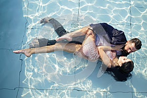 Romantic couple in love in swimming pool. Party in swimming pool. Fashionable pair of elegant people. Fashion couple in