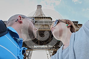 Romantic couple making selfie in front of Eiffel Tower while traveling in Paris, France. Students enjoy their vacation