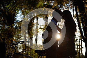 Romantic couple, man and attractive girl close together at tandem bicycle in dark autumn park.