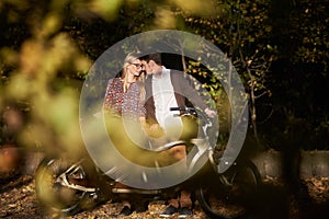 Romantic couple, man and attractive girl close together at tandem bicycle in dark autumn park.