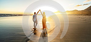 Romantic couple, man and woman holding hands enjoying sea sunset on beach during travel holidays vacation. Love, getaway,