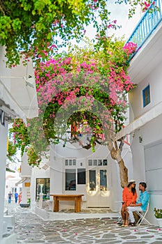 Romantic couple of men and women at the street of Mykonos Greek village in Greece