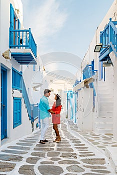 Romantic couple of men and women at the street of Mykonos Greek village in Greece