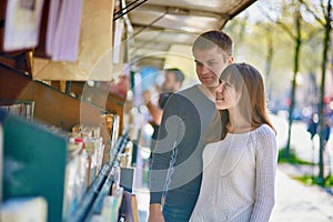 Romantic couple in Paris selecting a book from a bookseller