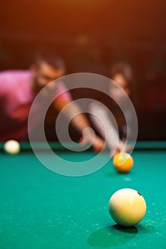 Romantic couple playing billiard in dark club