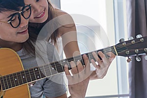 Romantic Couple playing guitar together happily in the room.close up