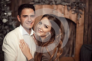 Romantic couple portrait in love. Cheerful Happy newlywed hugging in cozy wooden interior on winter holidays.