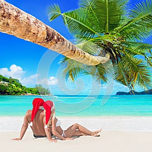 Romantic couple in red Christmas Santa hats sunbathe at tropical palm sandy island beach