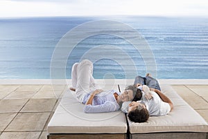 Romantic Couple Relaxing On Sunbeds By Infinity Pool