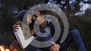 Romantic couple resting at bonfire, smiling, kissing and caressing