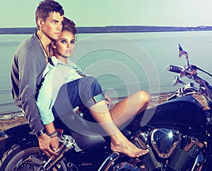 Romantic couple resting on lake shore, motorbike