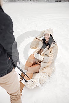 Romantic couple riding on a sled in forest at winter day
