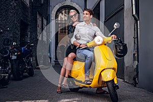 Romantic couple riding on vintage Italian scooter in the old narrow street of Europe