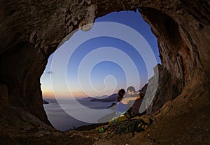 Romantic couple of rock climbers in cave at sunset
