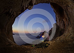 Romantic couple of rock climbers watching sunset from cave in cl