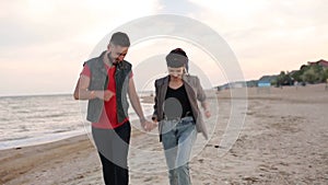 Romantic couple running holding hands on white sand beach near sea in slow motion. Boyfriend and girlfriend having fun