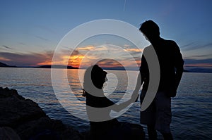 Romantic couple silhouette over sea sunset background