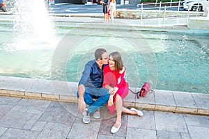 Romantic couple sitting on the bench near the city fountain and enjoying moments of happiness. Love, dating, romance. Lifestyle an