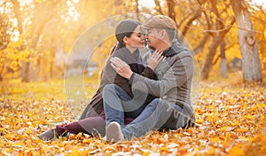Romantic Couple Sitting on Fall Foliage Nose To Nose With Closed Eyes in Autumn Suburb. Nice Man Hugs His Beloved Woman