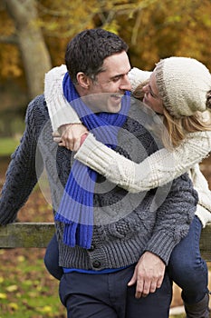 Romantic Couple Sitting On Fence In Autumn Woodland