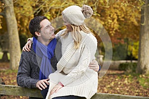 Romantic Couple Sitting On Fence In Autumn Woodland