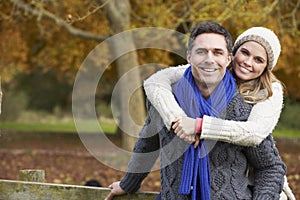 Romantic Couple Sitting On Fence In Autumn Woodland