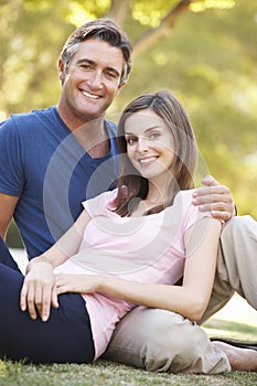 Romantic Couple Sitting On Grass In Summer Park
