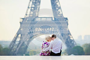 Romantic couple sitting near the Eiffel tower in Paris, France