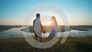 The romantic couple standing on a mountain top on a beautiful river background.