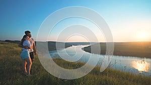 The romantic couple standing on a mountain top on a beautiful river background.