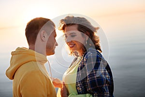 Romantic couple standing near the river at the sunset