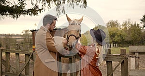 Romantic couple stroking a horse on pasture