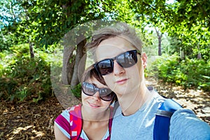 Romantic couple in sunglasses making selfie while walking in the summer forest. Local Traveling and relax in nature