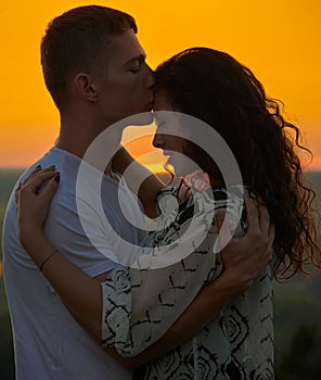 Romantic couple at sunset on outdoor, beautiful landscape and bright yellow sky, love tenderness concept, young adult people