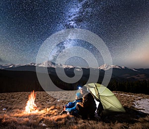 Couple tourists enjoying in the camping at night, having a rest under beautiful night sky full of stars and milky way