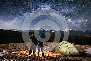 Romantic couple tourists enjoying in the camping at night under beautiful night sky full of stars and milky way