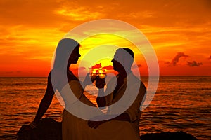Romantic couple at tropical beach with sunset in the background