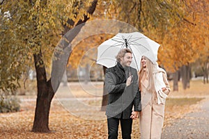 Romantic couple with umbrella walking in park