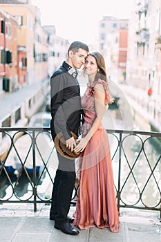 Romantic couple in Venice. Young beautiful couple standing on bridge of the Venice canal and hugging. Italy, Europe.